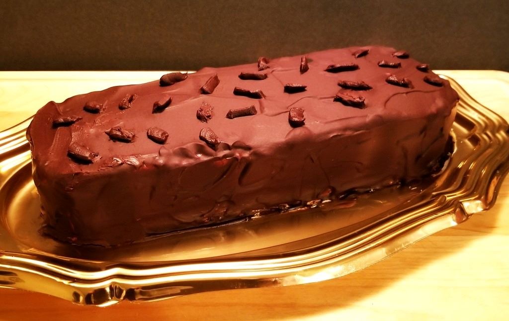 Stack of homemade vegan gansito cakes with chocolate glaze and shredded coconut exterior coating
